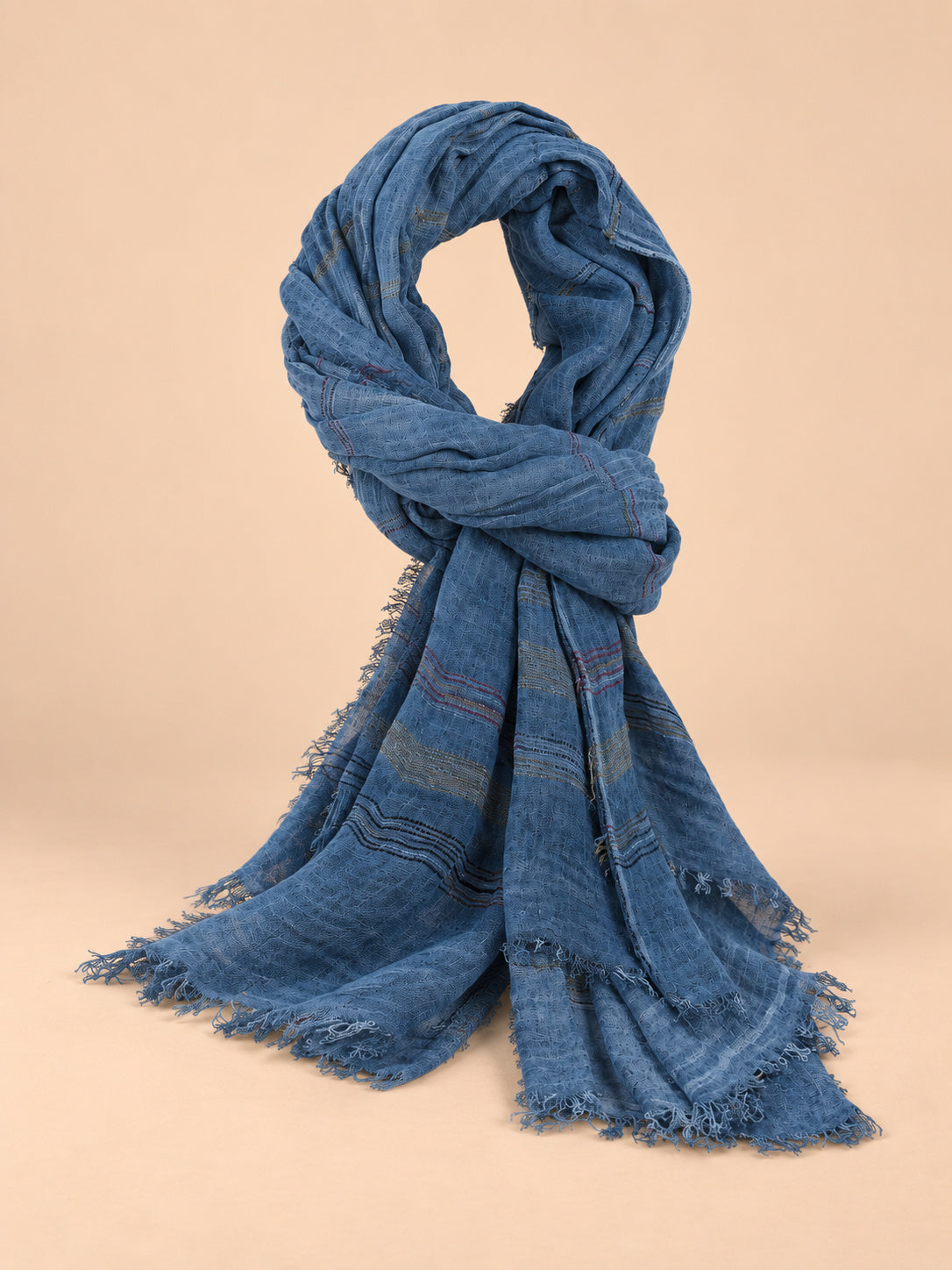 Écharpe homme rayée, bleu marine, vue de trois quarts sur fond pêche sable.