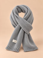 Bufanda lisa clásica de punto para invierno, wj2061, color gris, vista frontal, sobre fondo color arena y melocotón