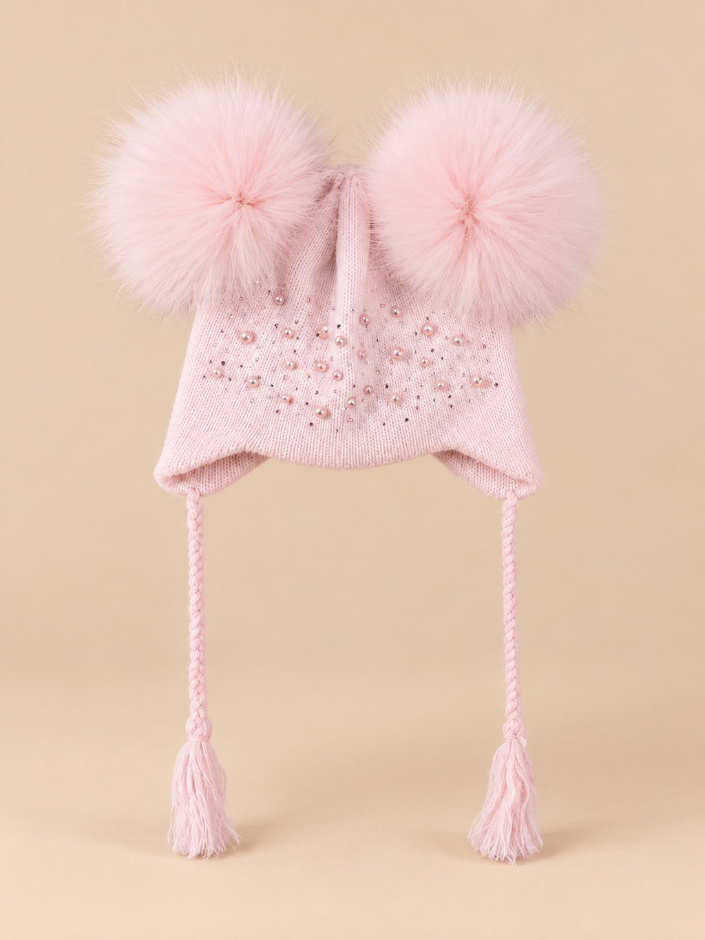 Gorro rosa infantil con dos pompones de pelo de mapache del mismo color, fotografiado de frente