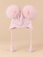 Gorro rosa infantil con dos pompones de pelo de mapache del mismo color, fotografiado de frente