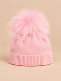 Gorro rosa infantil de mezcla de lana con pompón de pelo del mismo color, fotografiado de frente