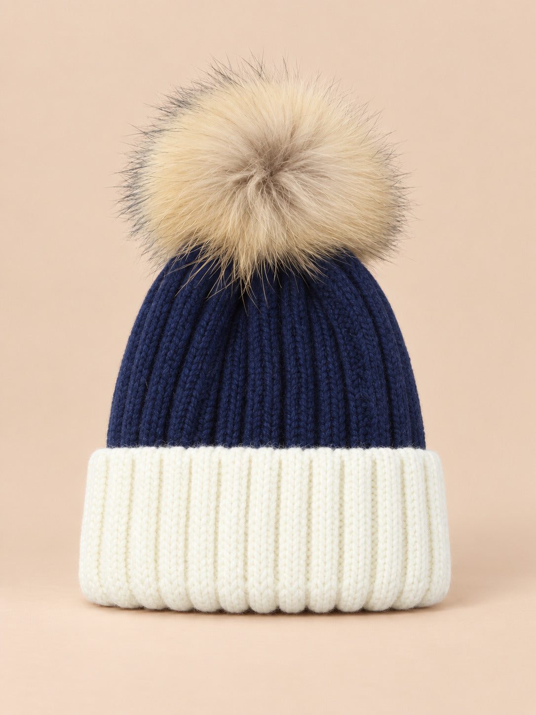 Bonnet enfant à pompon bleu fonce 2, vue de face sur fond pêche sable