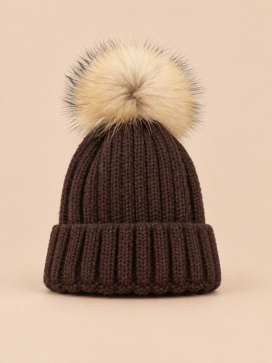 Bonnet enfant à pompon cafe, vue de face sur fond pêche sable