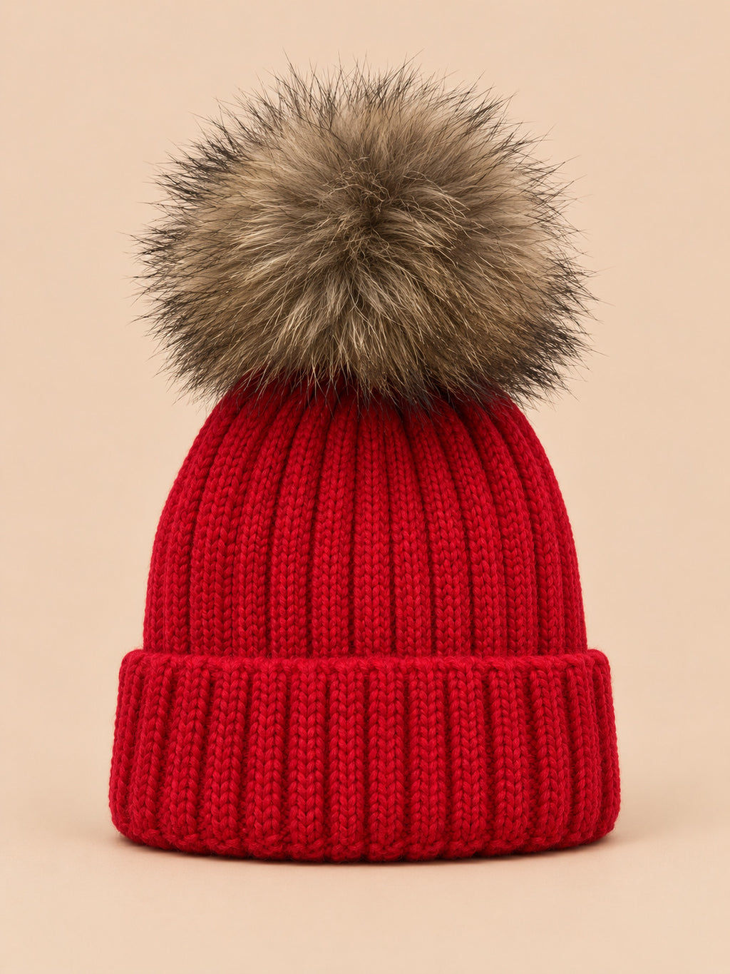 Gorro rojo infantil con pompón, parte del conjunto de gorro y bufanda, sobre fondo arena y melocotón