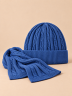 Conjunto de gorro y bufanda de lana gruesa jacquard, color azul, vista frontal, sobre fondo color arena y melocotón
