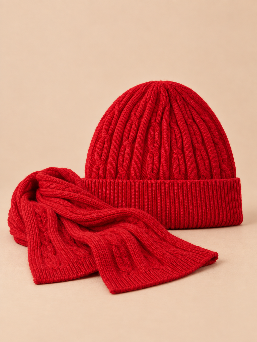 Ensemble bonnet à revers et écharpe en laine jacquard rouge, vue de face sur fond pêche sable.