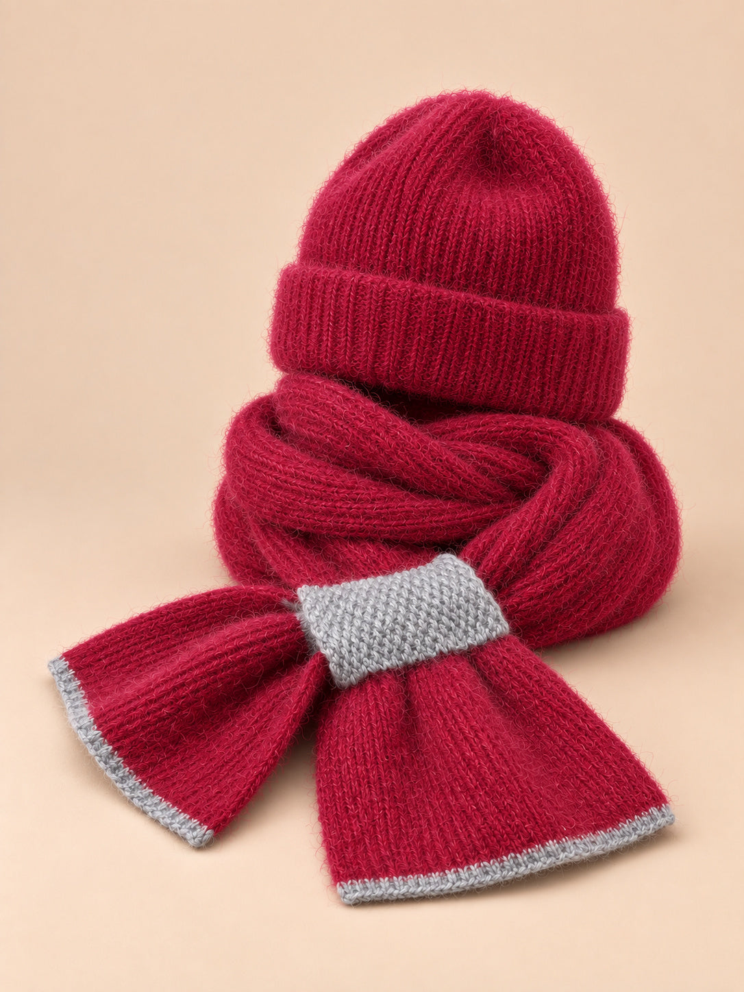Ensemble bonnet et écharpe peluche, bordeaux, vue de trois quarts sur fond pêche sable.