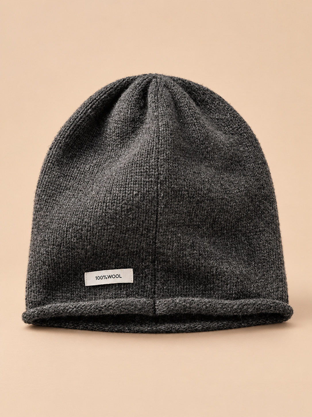 Bonnet femme en pure laine gris, vue de face, fond pêche sable
