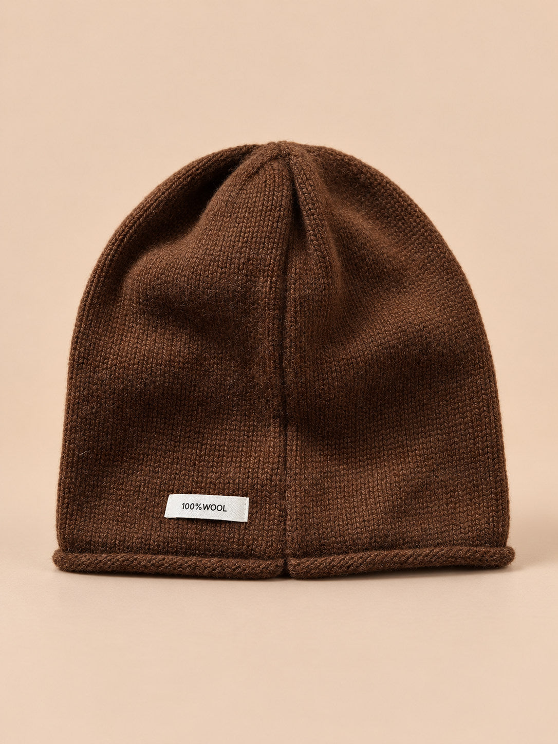 Bonnet femme en pure laine marron, vue de face, fond pêche sable