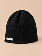Bonnet femme en pure laine noir, vue de trois quarts, fond pêche sable