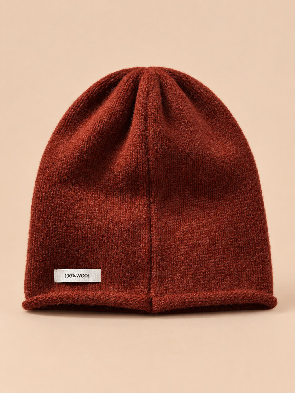 Bonnet femme en pure laine rouge, vue de face, fond pêche sable