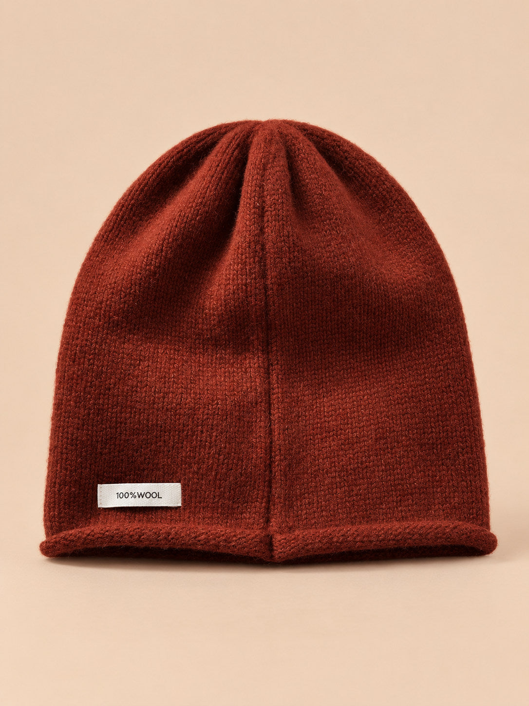 Bonnet femme en pure laine rouge, vue de face, fond pêche sable