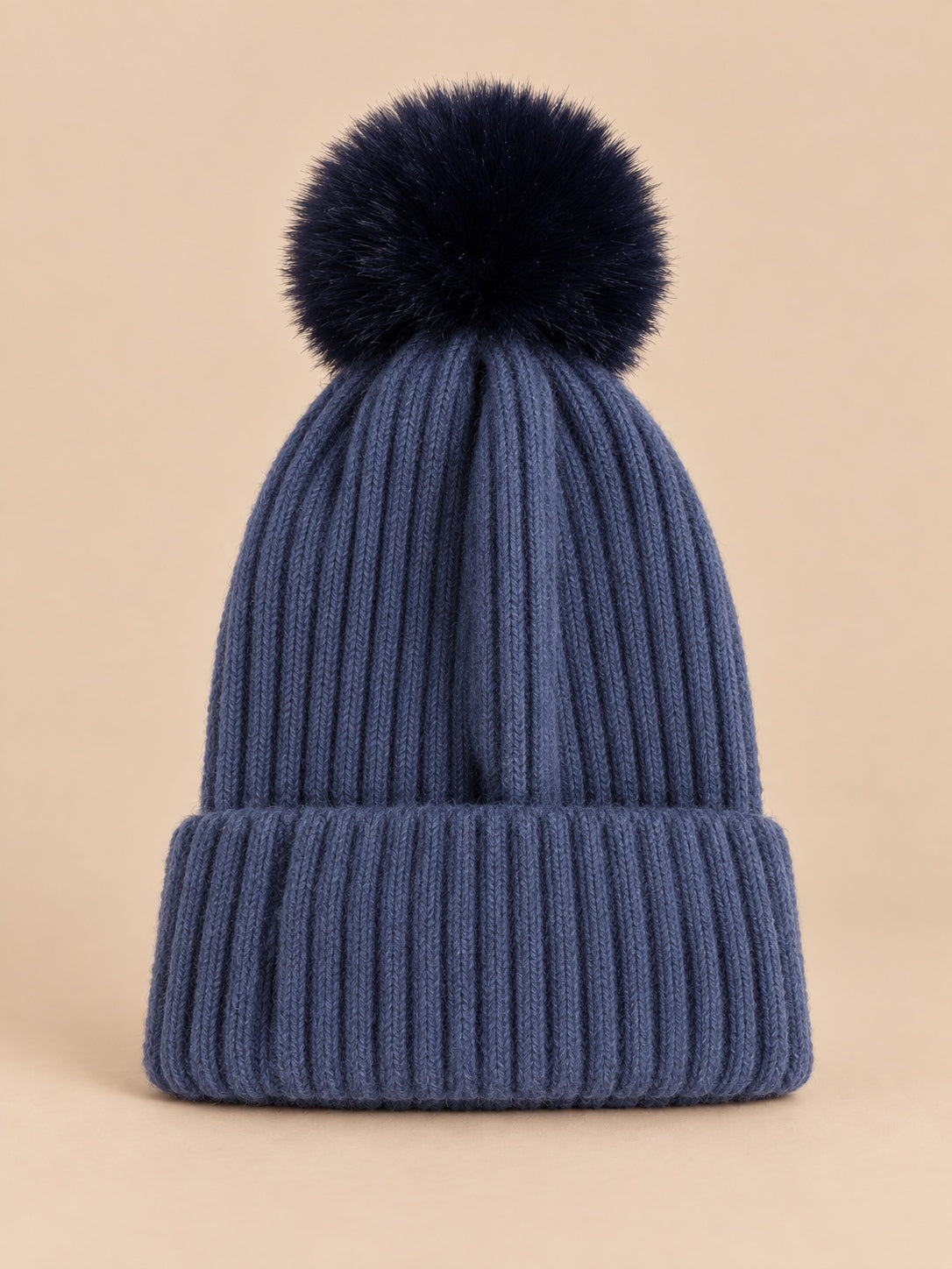 Bonnet de ski bleu marine sans logo à gros pompon foncé et revers côtelé, vue de face.