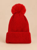 Bonnet de ski rouge sans logo, maille côtelée à revers et gros pompon assorti, vue de face.