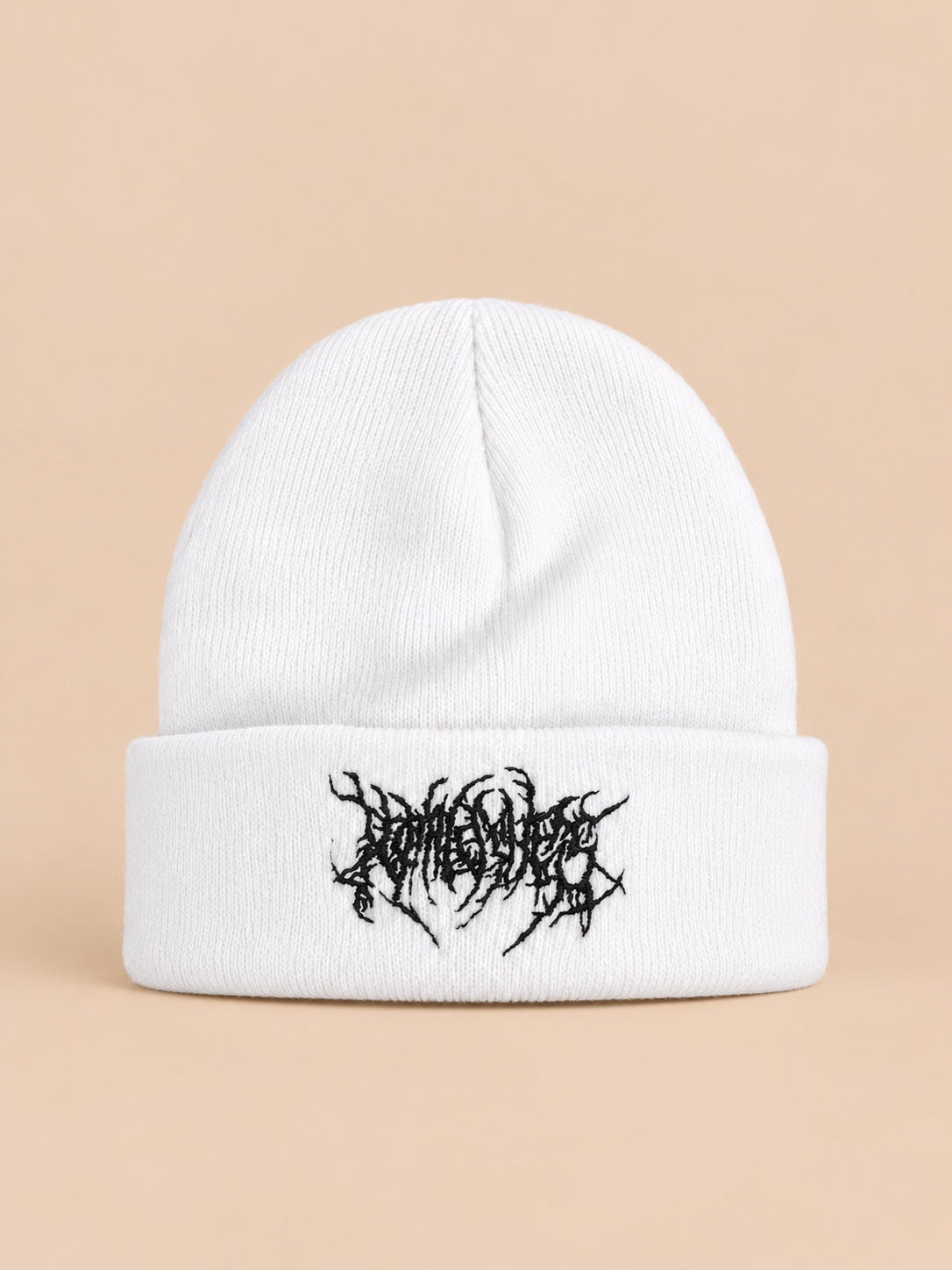 Bonnet en maille chaud blanc à broderie noire, vue de face sur fond pêche sable