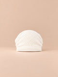 Bonnet oversize en maille blanc, vue de face sur fond pêche sable.