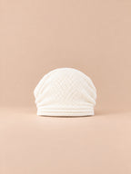 Bonnet oversize en maille blanc, vue de face sur fond pêche sable.