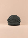 Gorro oversize de punto cálido y cortavientos, color gris oscuro, vista frontal, sobre fondo color arena y melocotón