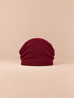 Bonnet oversize en maille rouge, vue de face sur fond pêche sable.
