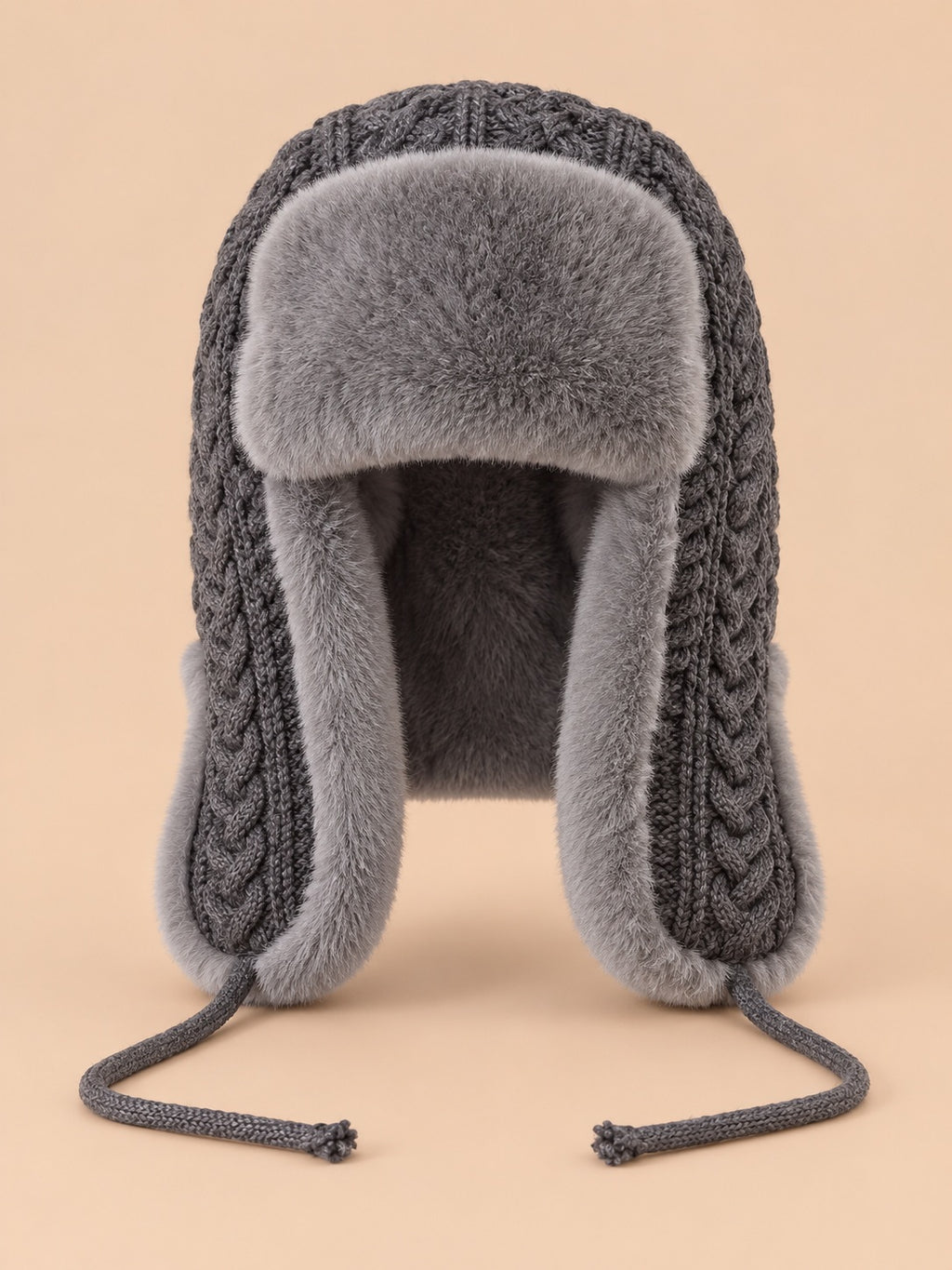 Gorro peruano de mujer con orejeras y cintas, color gris, vista frontal, sobre fondo color arena y melocotón