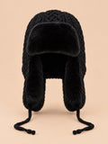 Gorro peruano de mujer con orejeras y cintas, color negro, vista frontal, sobre fondo color arena y melocotón