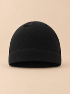 Gorro negro de tejido polar suave y cortavientos para bicicleta, fotografiado de frente sobre fondo beige
