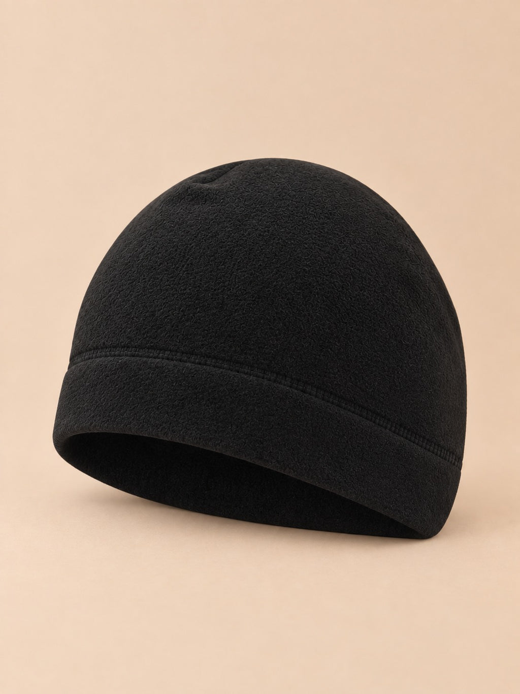 Bonnet polaire coupe-vent pour vélo noir, vue de trois quarts sur fond beige