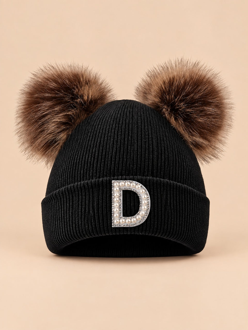 Gorro negro de mujer de tejido polar con letra D y orejas decorativas suaves, fotografiado de frente