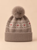 Gorro de cachemira color camel con pompón y orejeras, fotografiado sobre fondo arena y melocotón
