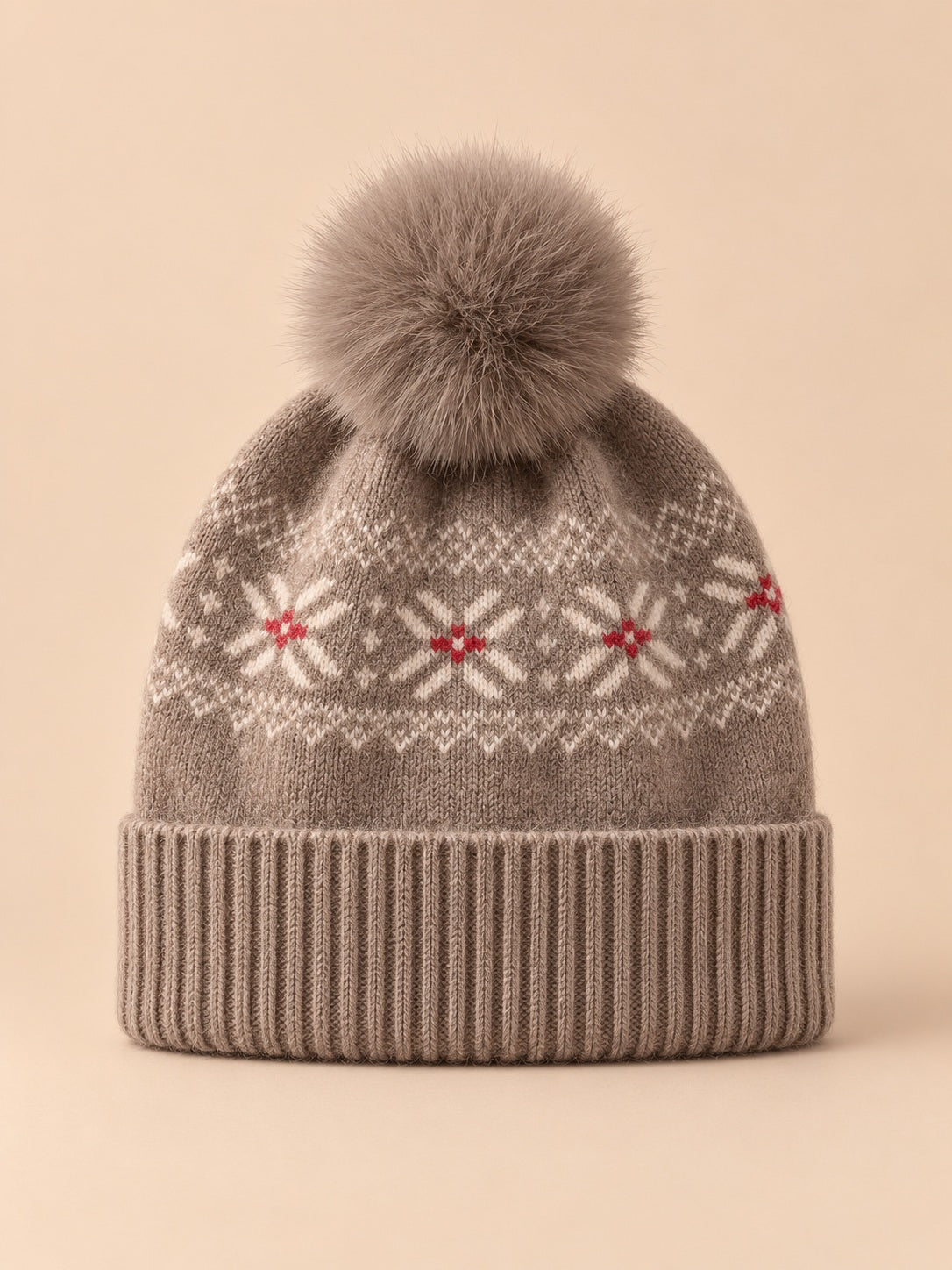 Bonnet cachemire camel à pompon et motif nordique, vue de face sur fond pêche sable