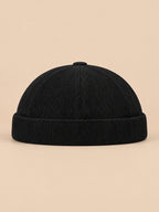 Gorro sin ala de pana a rayas para entretiempo, color negro, vista frontal, sobre fondo color arena y melocotón