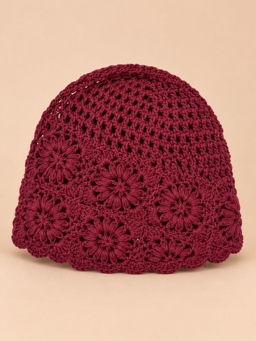 Bonnet turban femme bordeaux ajouré à fleurs au crochet, vue de face sur fond pêche sable