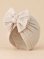 Gorro turbante de bebé niña de punto de algodón con lazo, color beige, vista de tres cuartos