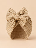 Gorro turbante de bebé niña de punto de algodón con lazo, colores beige y arena, vista frontal