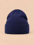 Gorro liso clásico de punto suave y ligero, color azul marino, vista frontal, sobre fondo color arena y melocotón