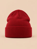 Gorro liso clásico de punto suave y ligero, color burdeos, vista frontal, sobre fondo color arena y melocotón