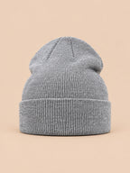 Bonnet uni classique en maille gris clair, vue de face sur fond pêche sable