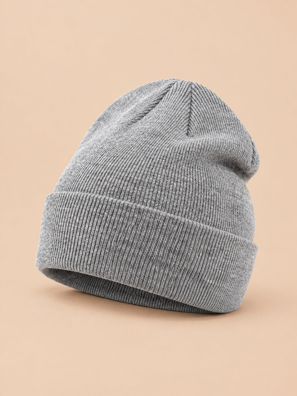 Bonnet uni classique en maille gris clair, vue trois quarts sur fond pêche sable