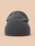 Gorro liso clásico de punto suave y ligero, color gris oscuro, vista frontal, sobre fondo color arena y melocotón