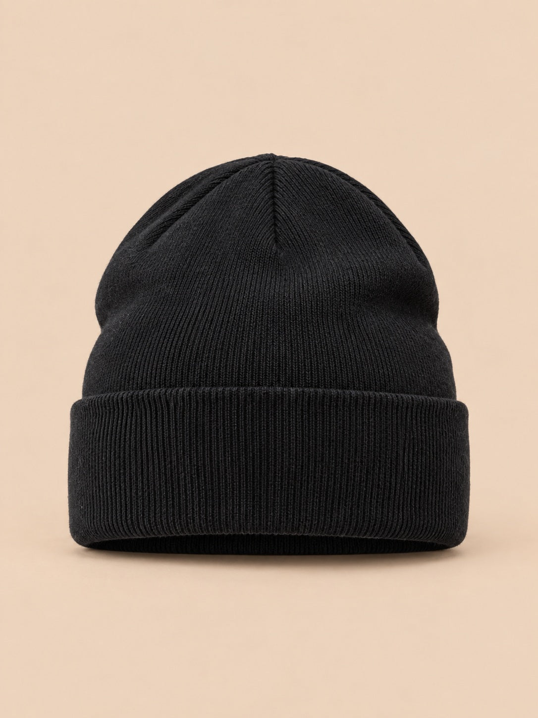 Bonnet uni classique en maille noir, vue de face sur fond pêche sable