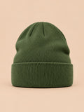 Gorro liso clásico de punto suave y ligero, color verde, vista frontal, sobre fondo color arena y melocotón