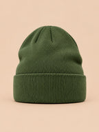 Gorro liso clásico de punto suave y ligero, color verde, vista frontal, sobre fondo color arena y melocotón